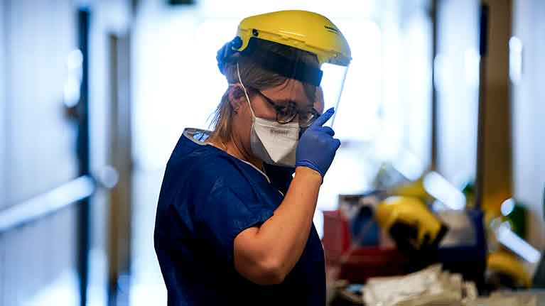 عاملة في الميدان الصحي ترفع قناعها الواقي في آخر نوبتها في العمل المضني في العناية بالمصابين بكوفيد-19
