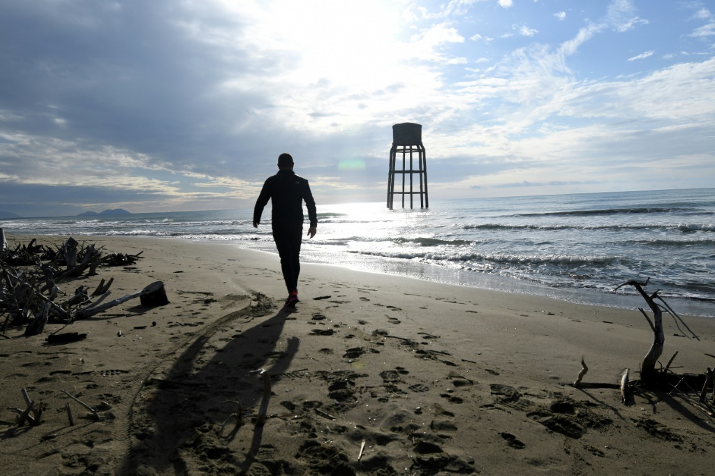  رجل يسير قرب برج مائي مغمور عند ساحل الأدرياتيكي في منطقة سيمان الألبانية في 18 تشرين الثاني/نوفمبر 2021