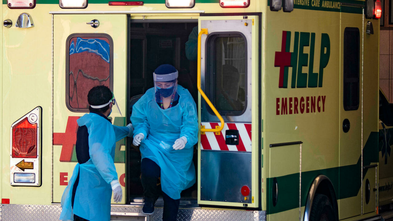 عامل صحي يساعد زميلاً على الخروج من سيارة إسعاف في سانتياغو، تشيلي، في 15 أيار/مايو 2021