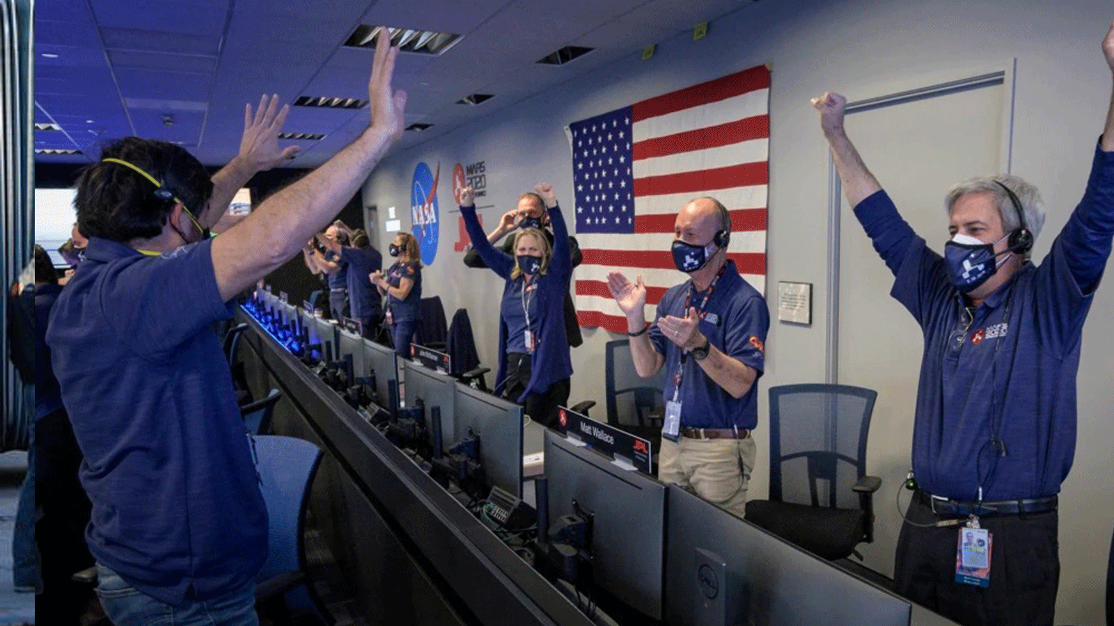 مراقبو التحكم في الأرض في مختبر الدفع النفاث التابع لوكالة ناسا في باسادينا، كاليفورنيا، يرفعون أذرعهم في الهواء ابتهاجاً بهبوط المركبة الجوالة المثابرة على سطح المريخ
