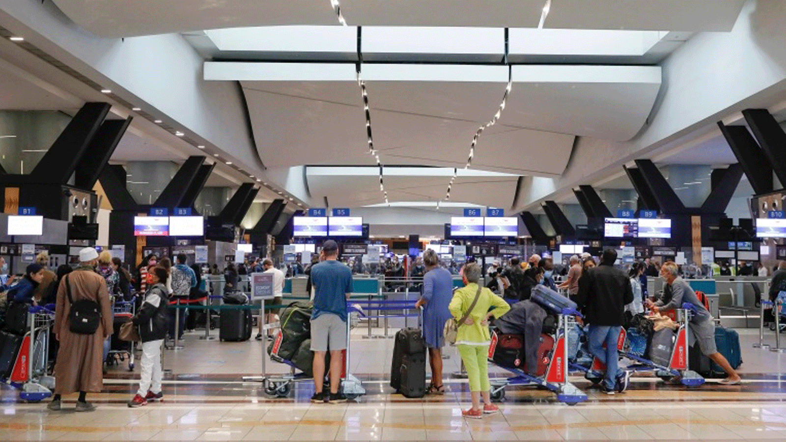 المسافرون يصطفون عند مكتب تسجيل الوصول في مطار أو آر تامبو الدولي في جوهانسبرج بعد أن حظرت عدة دول الرحلات الجوية من جنوب أفريقيا