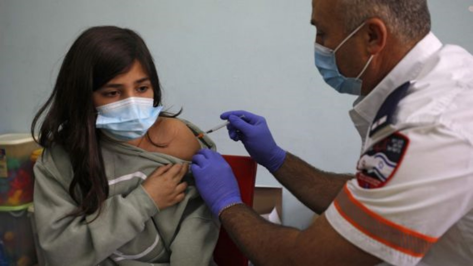 عامل صحي إسرائيلي يعطي جرعة من لقاح كوفيد-19 لطالبة في المدرسة.