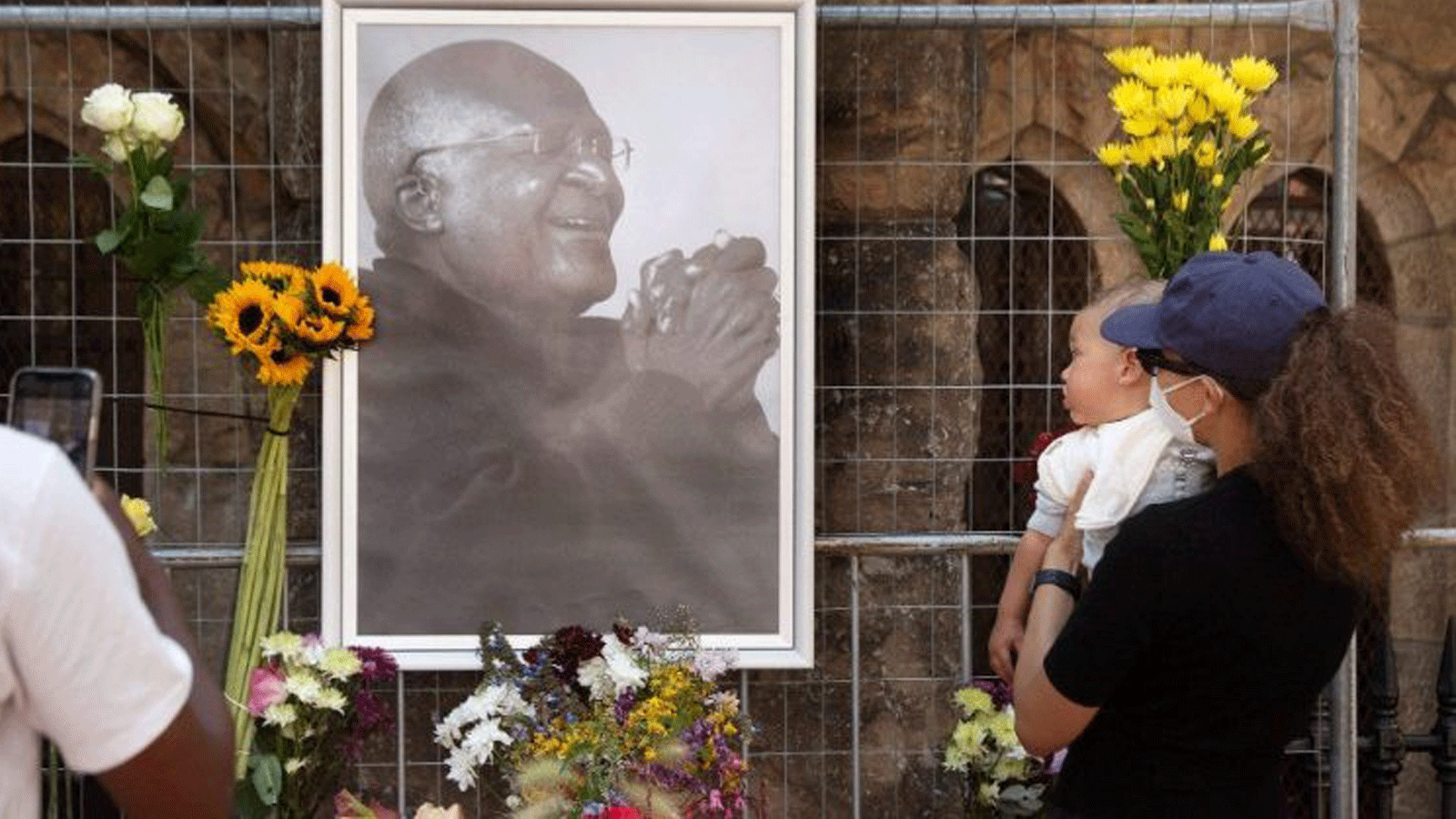 الناس يضعون الزهور على جدار كاتدرائية القديس جورج إحياءً لذكرى ديزموند توتو، الحائز على جائزة نوبل للسلام.