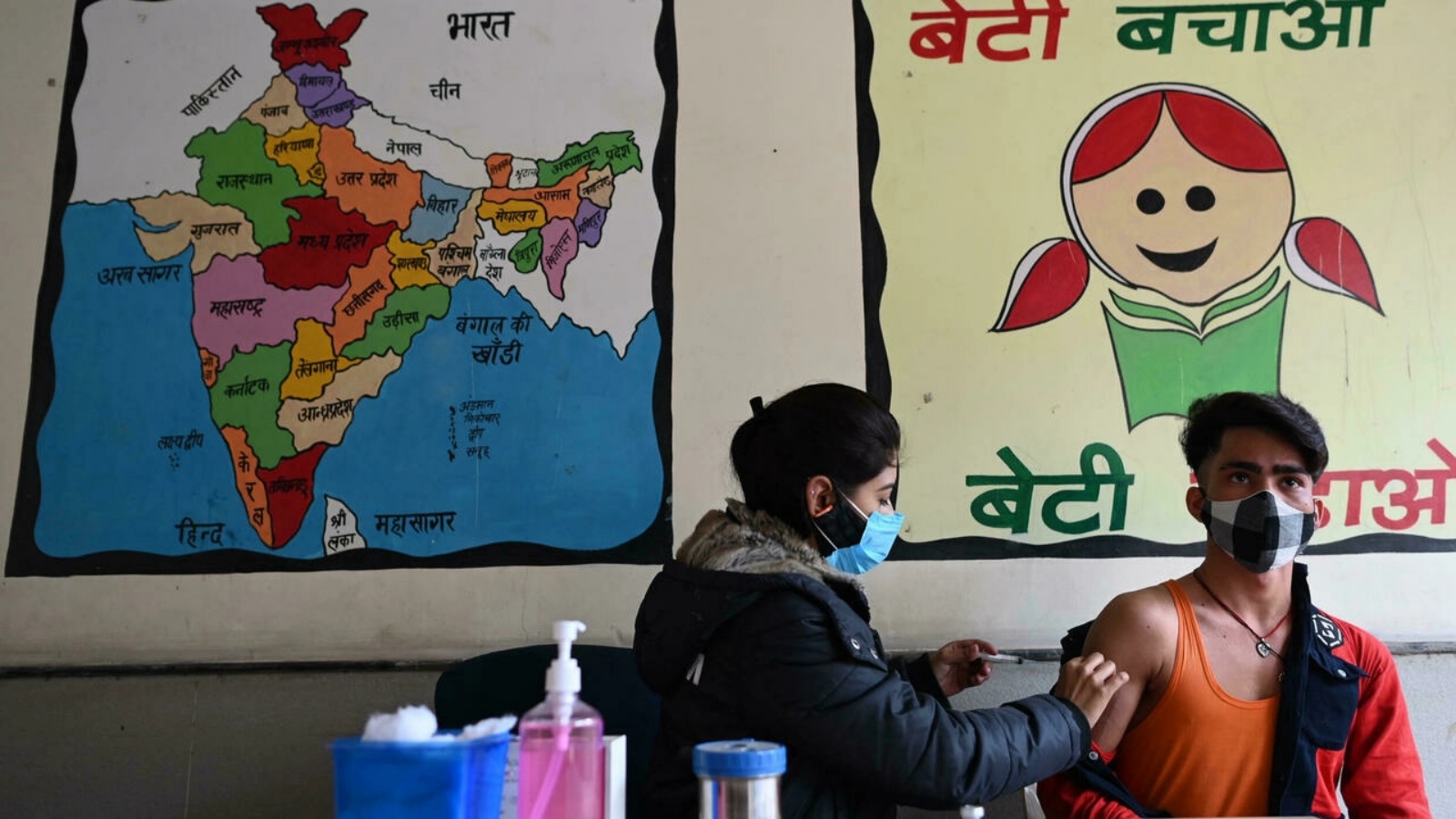 عاملة صحة تعطي جرعة من لقاح كورونا كوفيد-19 لشاب في الهند