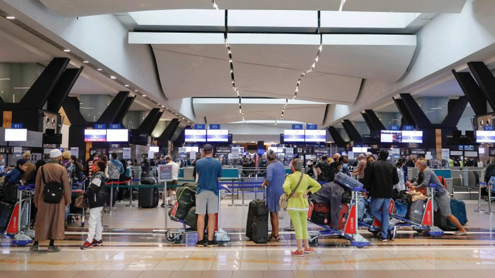 المسافرون يصطفون عند مكتب تسجيل الوصول في مطار أو آر تامبو الدولي في جوهانسبرج بعد أن حظرت عدة دول الرحلات الجوية من جنوب أفريقيا