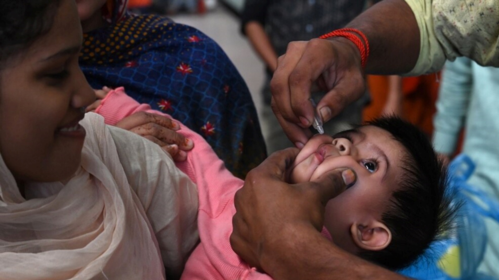 عامل صحي باكستاني يعطي قطرات شلل الأطفال لطفل في محطة سكة حديد خلال حملة التطعيم ضد شلل الأطفال في لاهور في 5 نوفمبر 2021