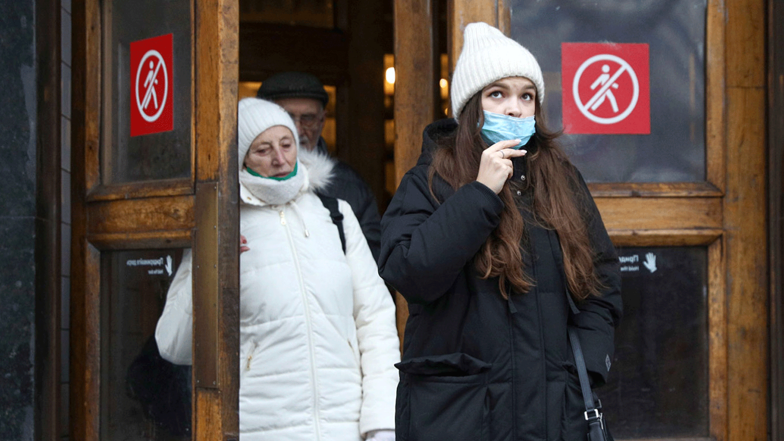سيدتان روسيتان تضعان قناع الوجه على مدخل أحد المطاعم الروسية