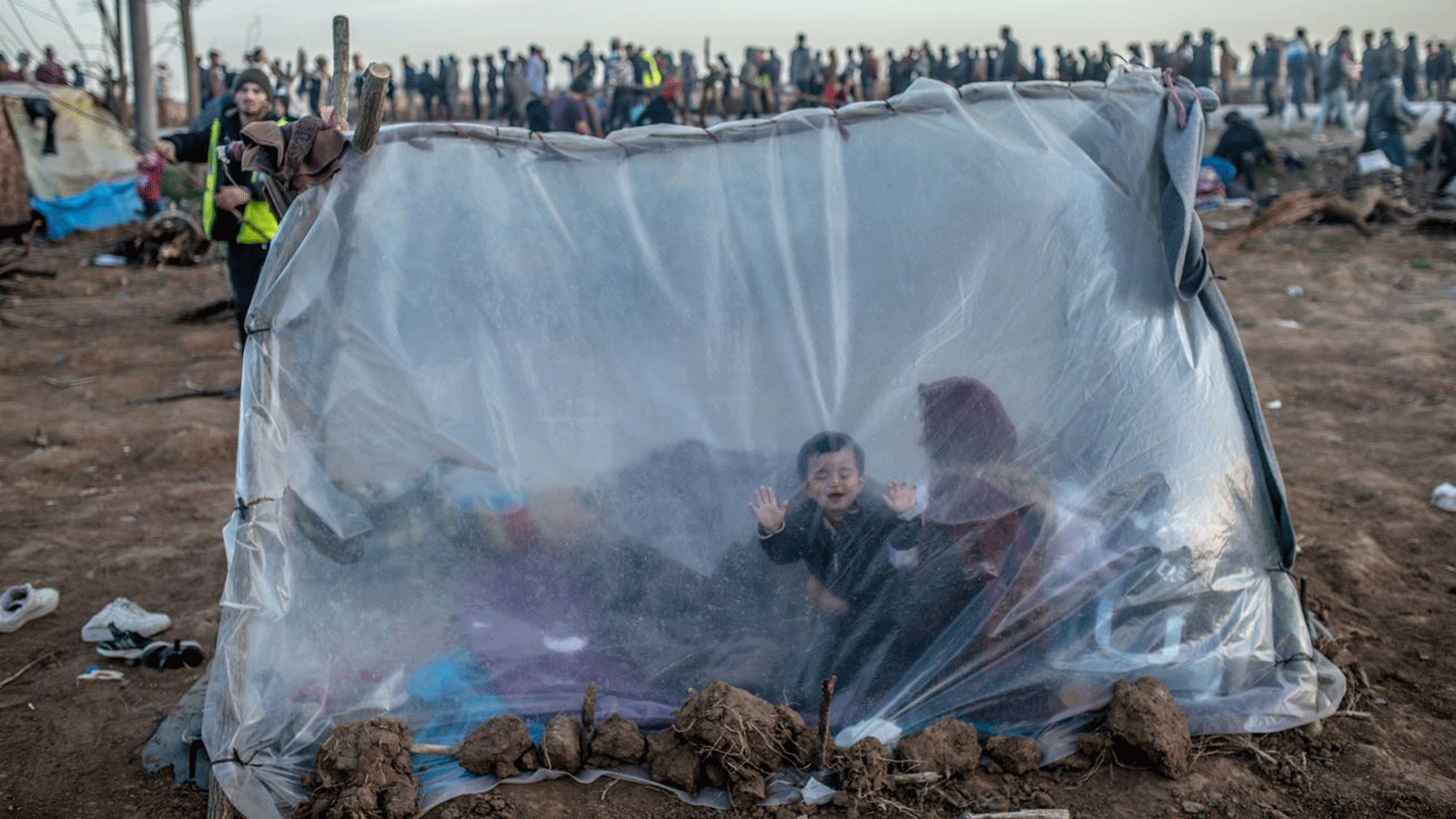 سيدة سورية تجلس في خيمة مع ابنها أمام معبر بازاركول الحدودي إلى اليونان، في أدرنة