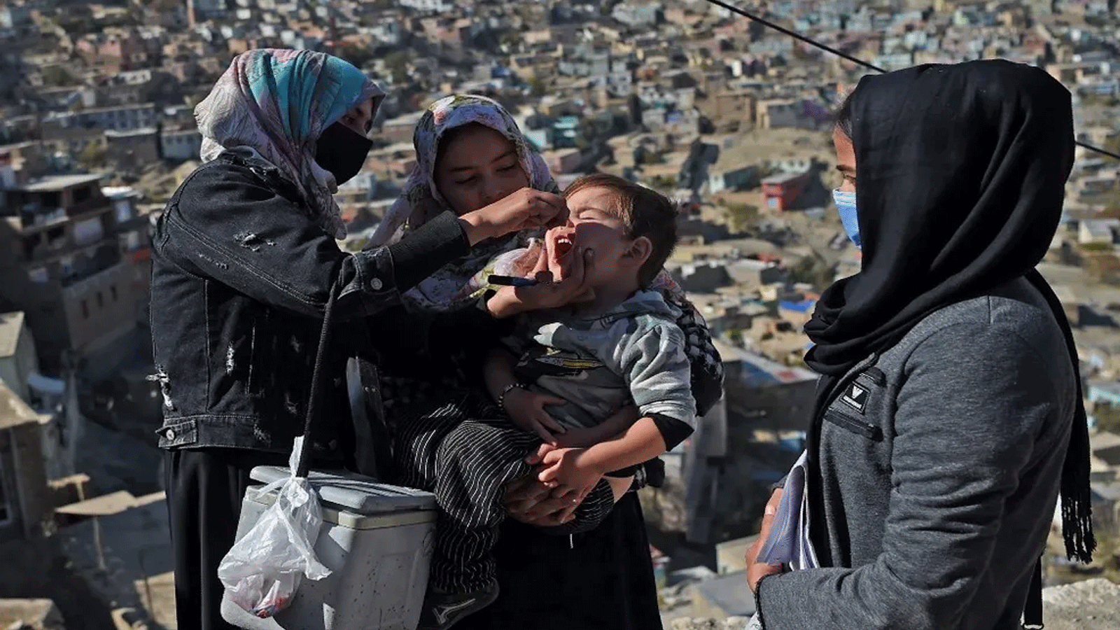 عاملٌ صحي (يسار) يعطي لقاح شلل الأطفال لطفلة خلال حملة تلقيح في الأحياء القديمة من كابول، أفغانستان، في 8 تشرين الثاني\نوفمبر 2021