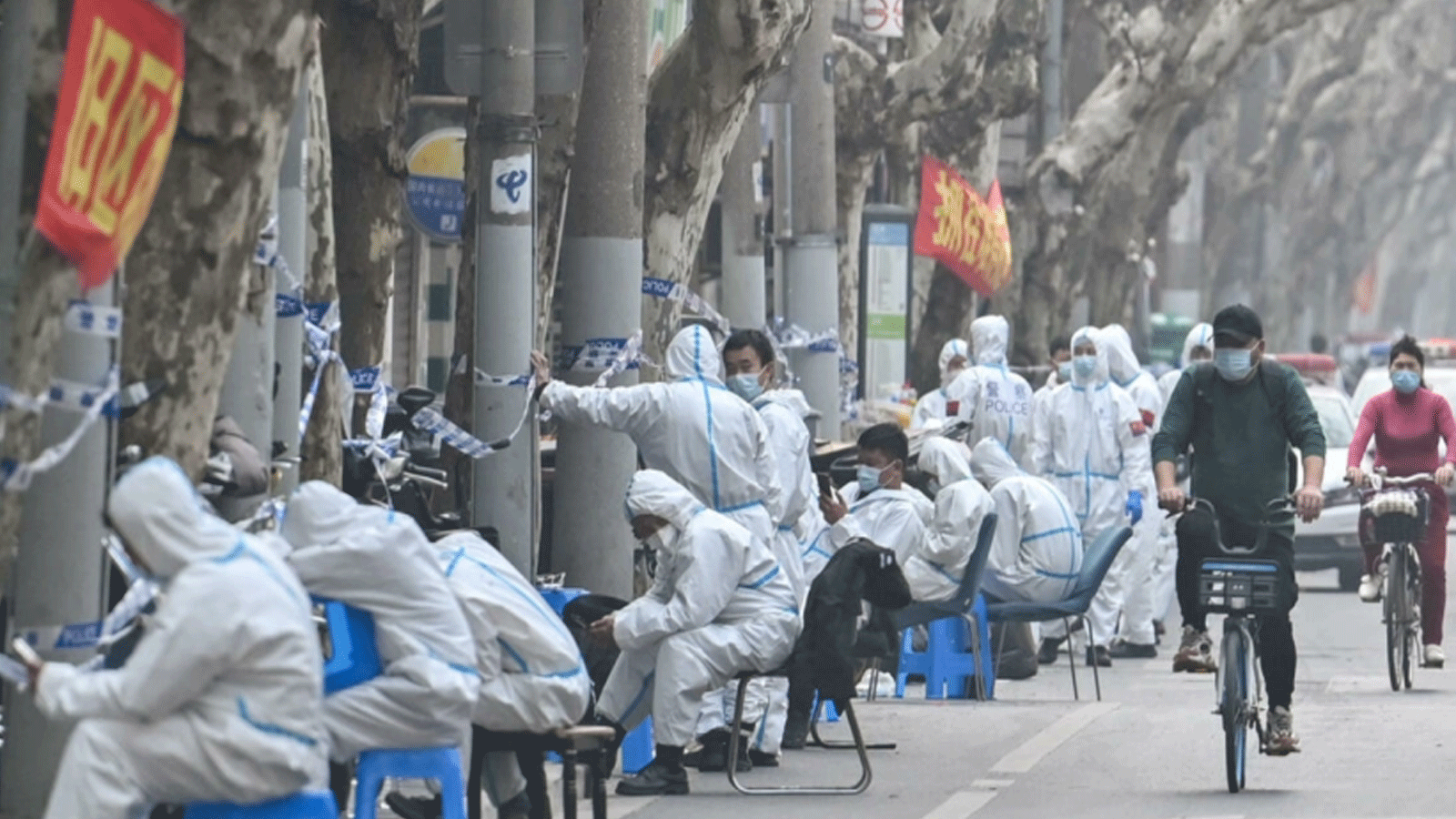 عمال يرتدون ملابس واقية يجلسون بالقرب من منطقة مغلقة بعد اكتشاف حالات جديدة لـ Covid-19 في شنغهاي في 14 آذار\ مارس 2022