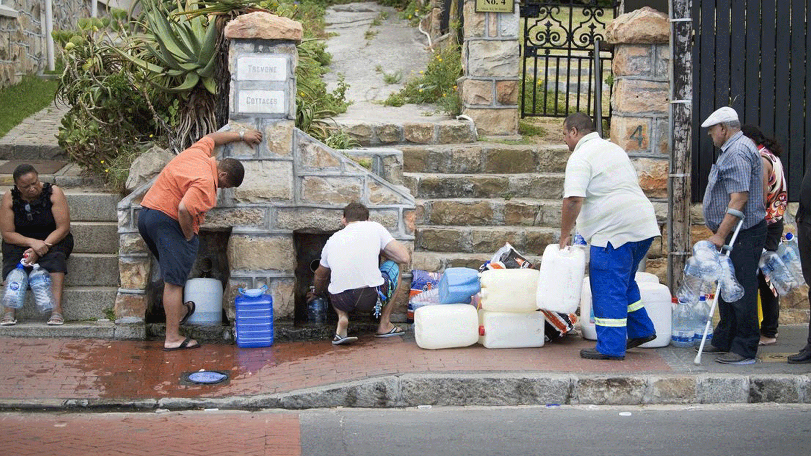  الناس يجمعون مياه الشرب من الأنابيب التي تغذيها ينابيع تحت الأرض، في سانت جيمس، على بعد حوالي 25 كيلومترًا من وسط المدينة. 19 كانون الثاني\ يناير 2018 في في كيب تاون