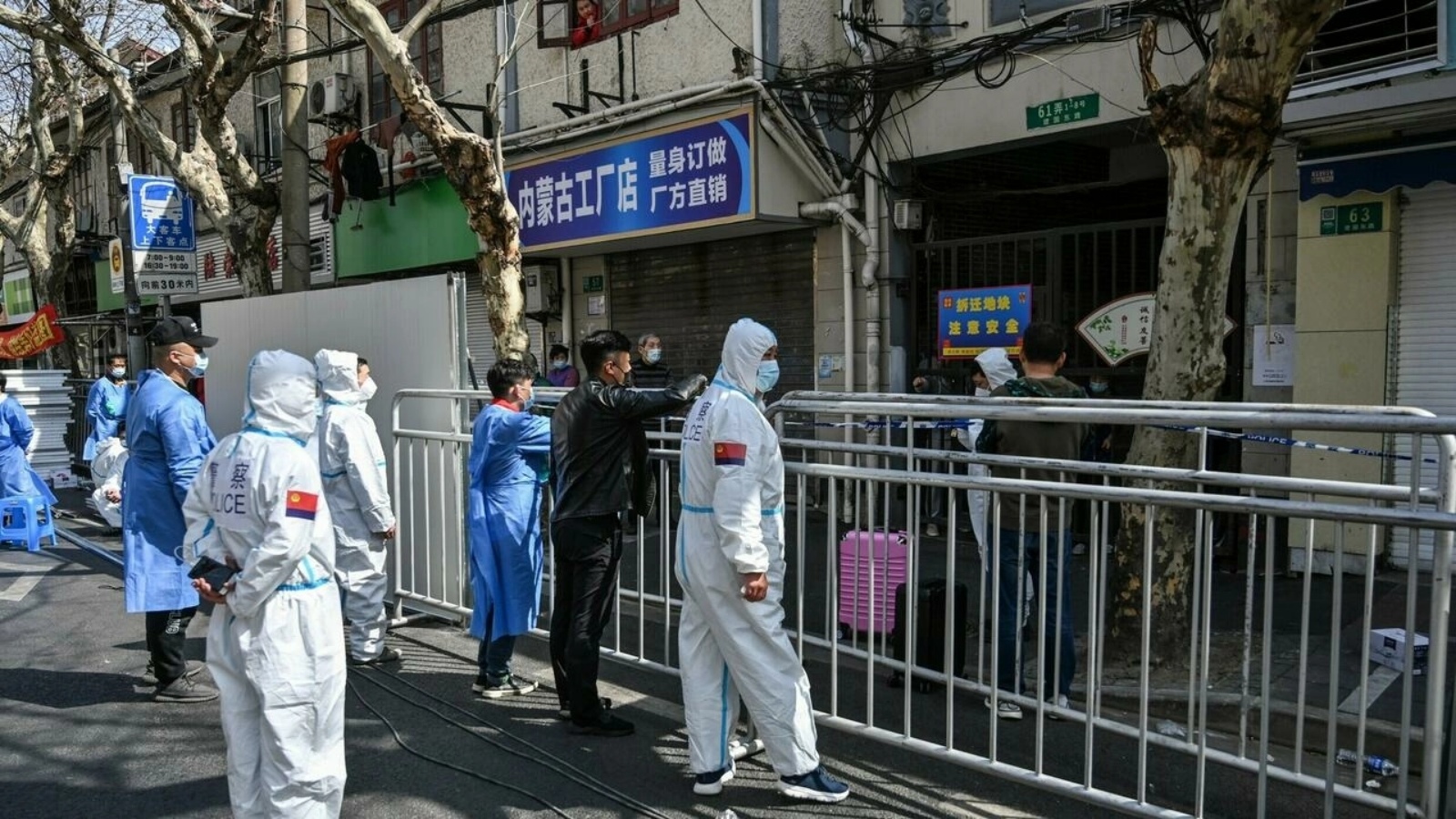الشرطة ومسؤولون في مجال الصحة يتحدثون مع سكان في أحياء تم عزلها بعد اكتشاف إصابات بكوفيد فيها في شنغهاي في 15 مارس 2022