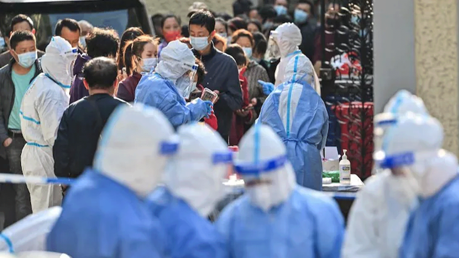 عاملون صحيون يرتدون معدات واقية لاختبار الأشخاص للكشف عن فيروس كورونا Covid-19 بمجمع في شنغهاي في 23 آذار\مارس 2022