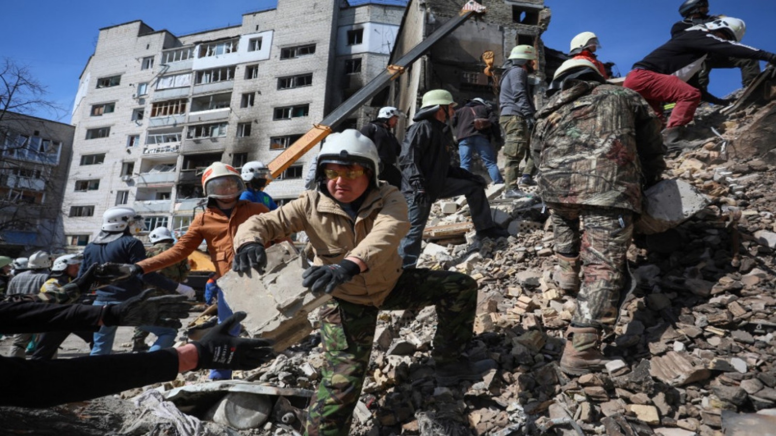 متطوعون يساعدون رجال الإنقاذ في إزالة اجزاء مبنى مدمر في بلدة بوروديانكا، شمال غرب كييف، 7 أبريل 2022.