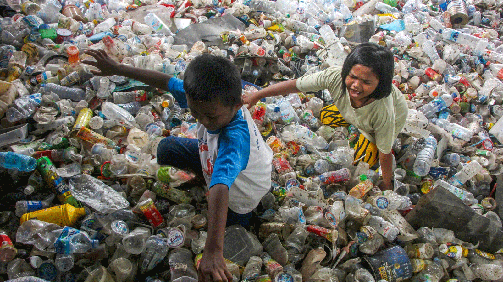 أطفال يلعبون في أكوام من النفايات البلاستيكية تم جمعها لإعادة تدويرها في ماكاسار، إندونيسيا. في شباط\ فبراير 2022.