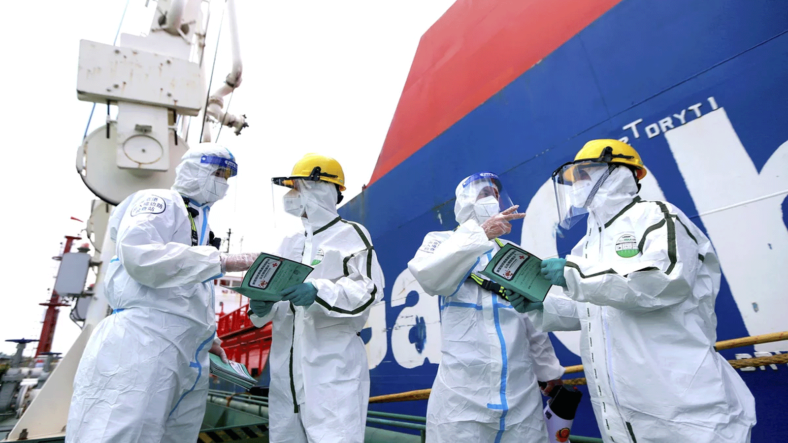  يرتدي ضباط الشرطة (اليسار والثاني من اليمين) ملابس واقية أثناء شرحهم كيفية مكافحة انتشار Covid-19 للعاملين في ميناء نانجينغ بمقاطعة جيانغسو شرق الصين في 4 آب\ أغسطس 2021.