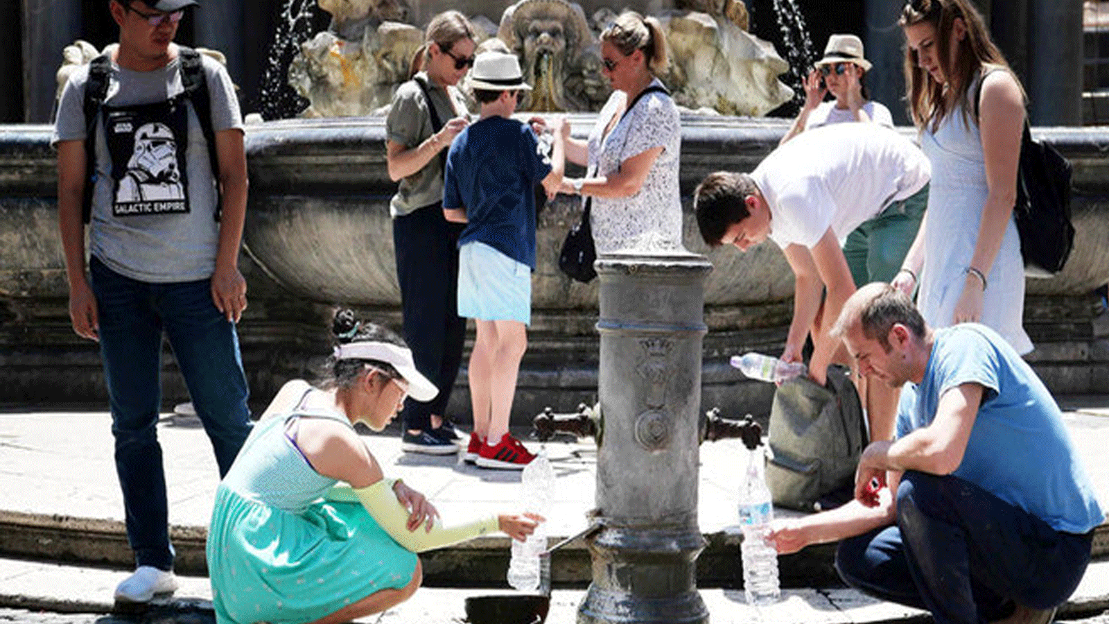  السائحون يملؤون زجاجاتهم من نافورة عامة لينعشوا أنفسهم خلال موجة حارة صيفية غير معتادة في 24 حزيران\يونيو 2019 في روما.