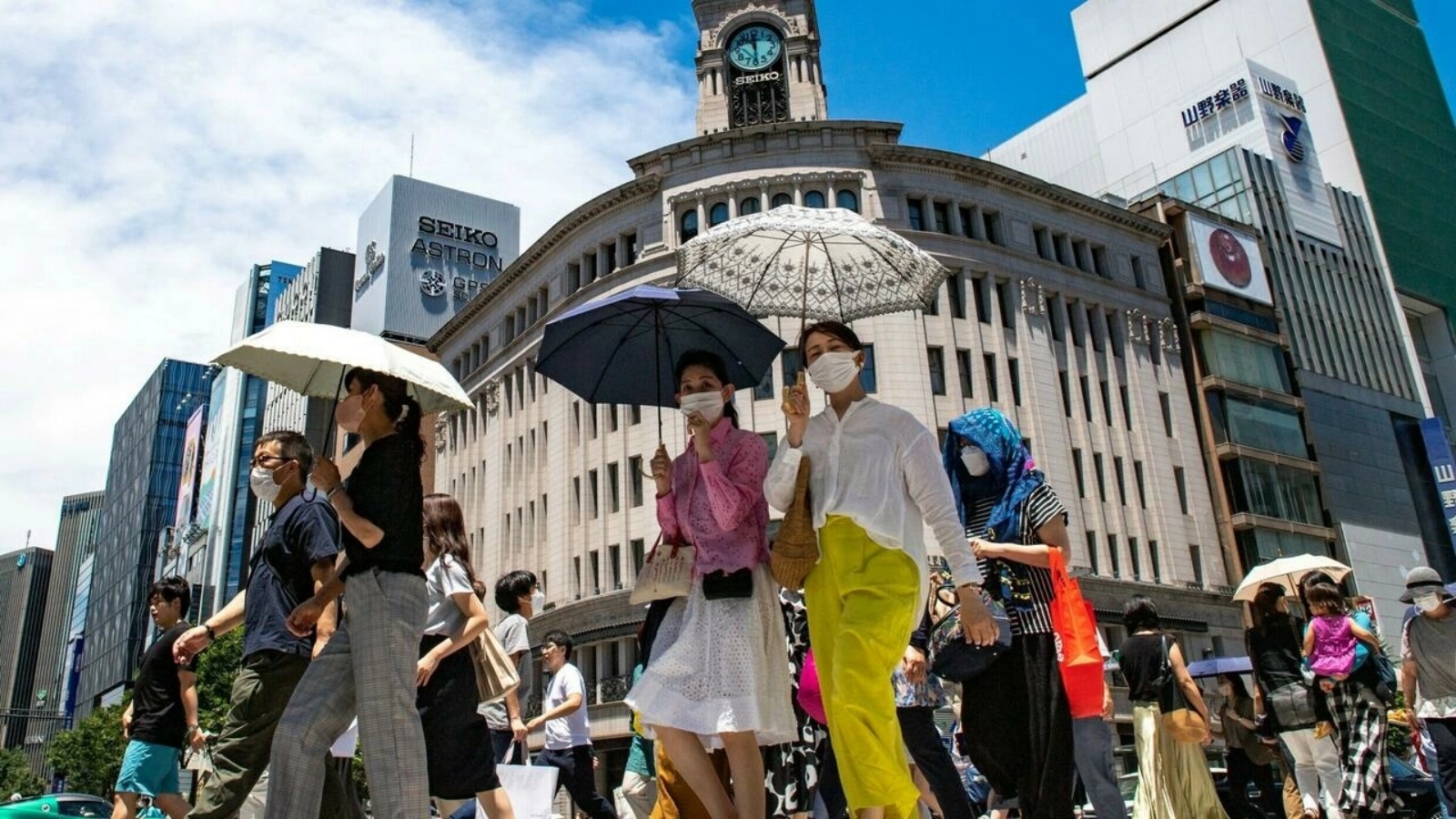 مارة في حي غينزا في طوكيو يستعينون بمظلات بسبب درجات الحرارة المرتفعة في 26 يونيو 2022