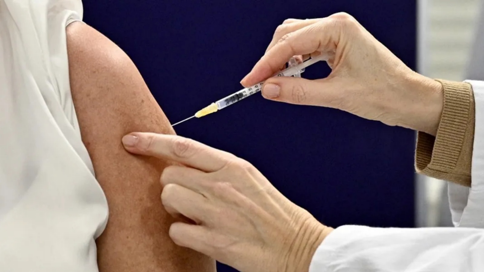 عاملة صحة تعطي جرعة من لقاح كورونا كوفيد-19