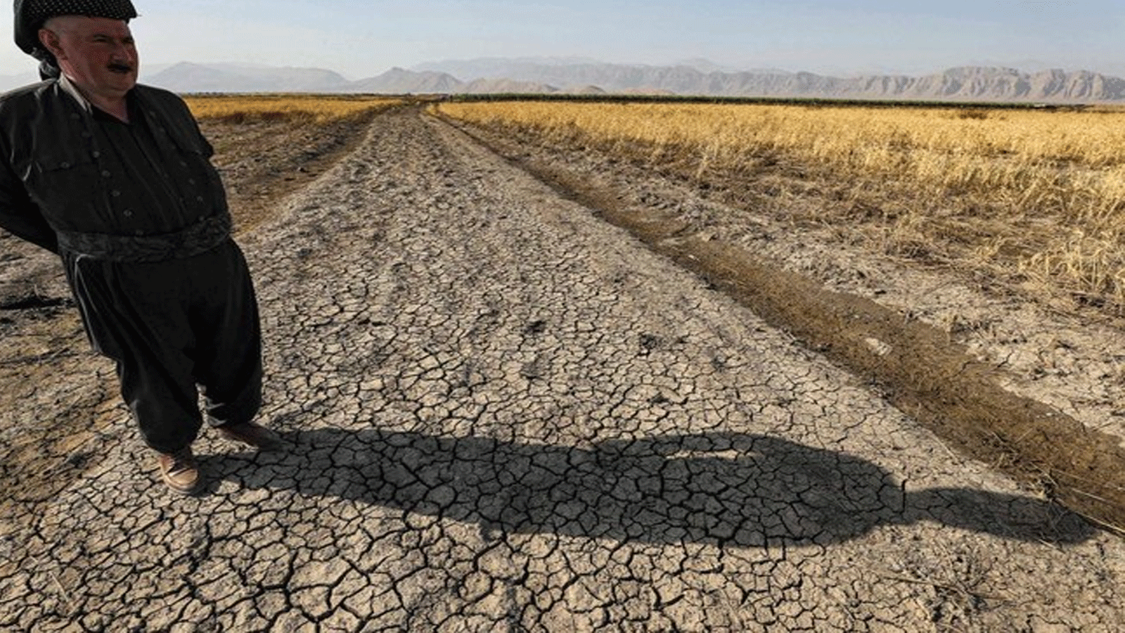 مزراع كردستاني يقف على أرض زراعية جافة