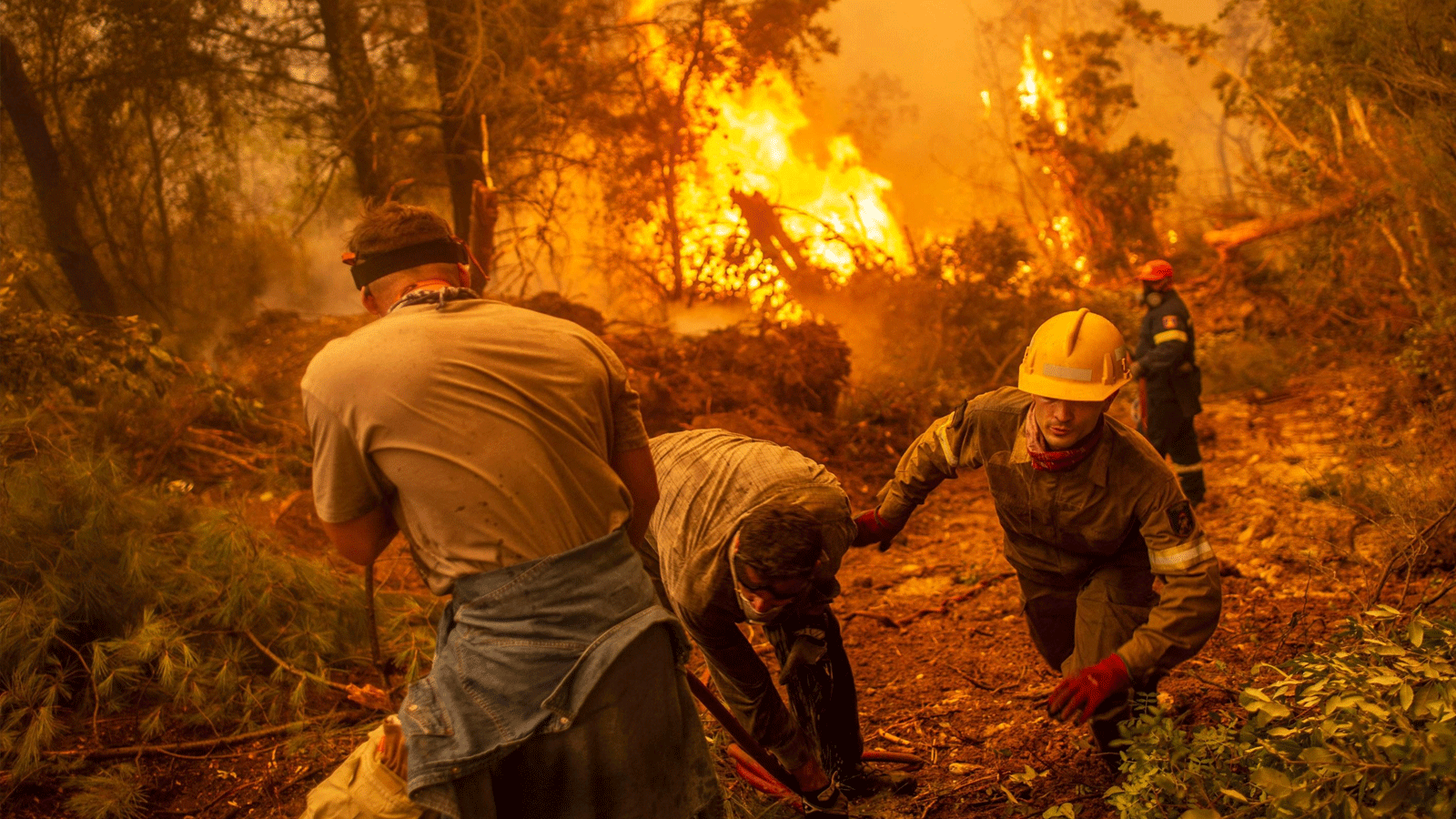 رجال الإطفاء والمتطوعون يستخدمون خرطوم مياه بالقرب من حريق محترق في محاولة لإخماد حريق في قرية غلاتسونا على جزيرة إيفيا (Euboea)، اليونان. 9 آب\أغسطس 2021