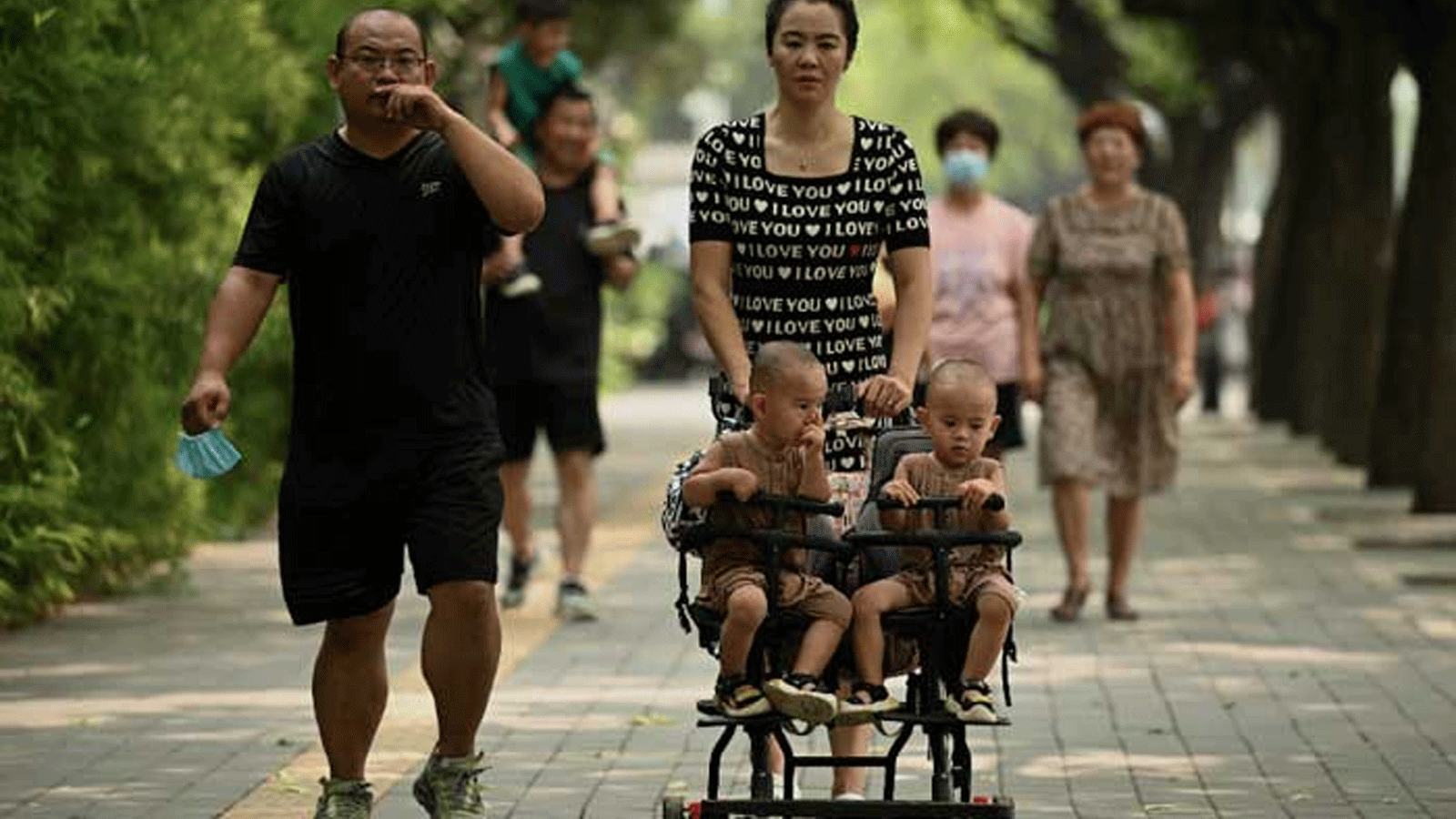 امرأة تدفع عربة مع توأمين على طول أحد شوارع بكين. في 2 أغسطس\ آب 2022 