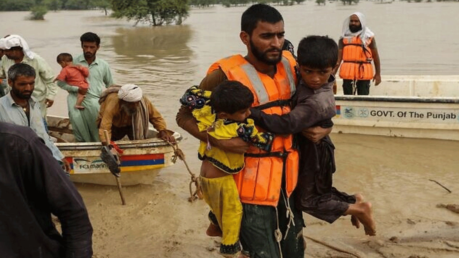 عمال الإنقاذ يساعدون في إجلاء الباكستانيين المتضررين من الفيضانات من منازلهم التي ضربتها الفيضانات بعد هطول أمطار موسمية غزيرة في منطقة راجانبور بمقاطعة البنجاب في 27 آب\ أغسطس 2022.