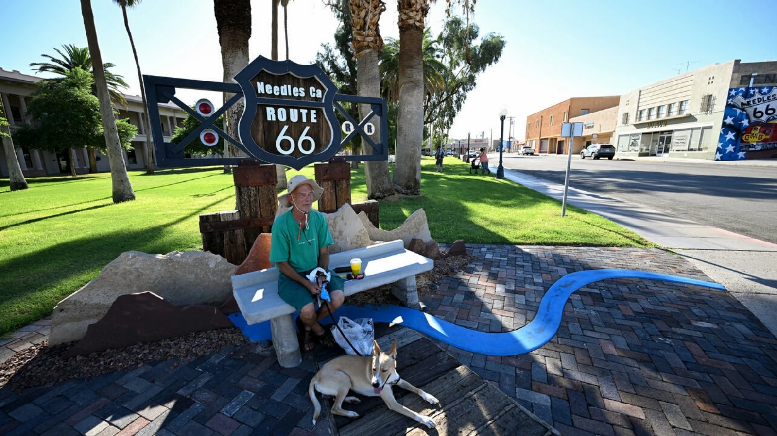رجل في الظل مع كلبه في نيدلز في كاليفورنيا حيث سجلت أعلى درجات الحرارة التي تجاوزت 100 درجة فهرنهايت قبل الساعة 9 صباحًا في 31 أغسطس 2022 