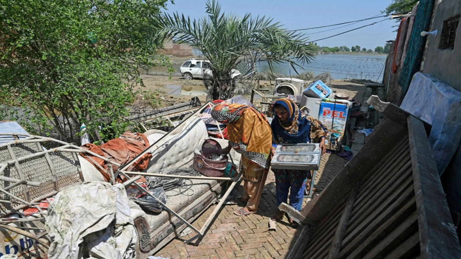  أفراد عائلة الحسين يحاولون إنقاذ ممتلكاتهم من منزلهم الذي دمرته الفيضانات في فاضيلبور، مقاطعة البنجاب