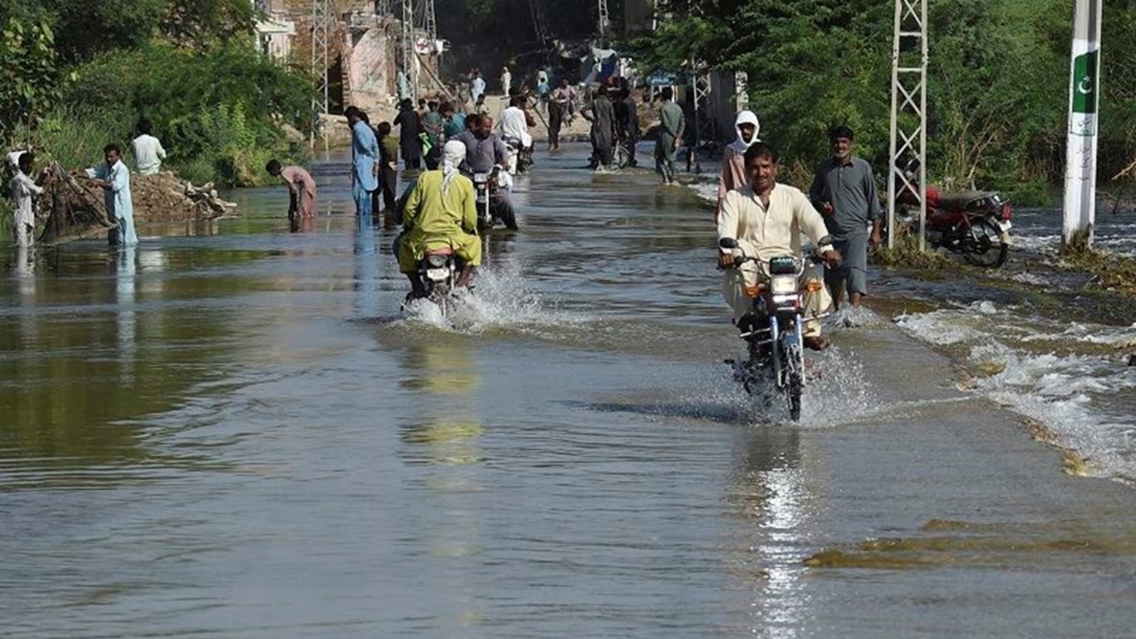 يشق السكان طريقهم على طول شارع غمرته المياه بعد هطول أمطار موسمية غزيرة في باكستان