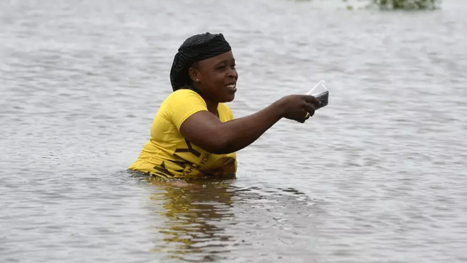 امرأة تمشي في طريق غمرته المياه بعد هطول أمطار غزيرة في واوا بولاية أوغون