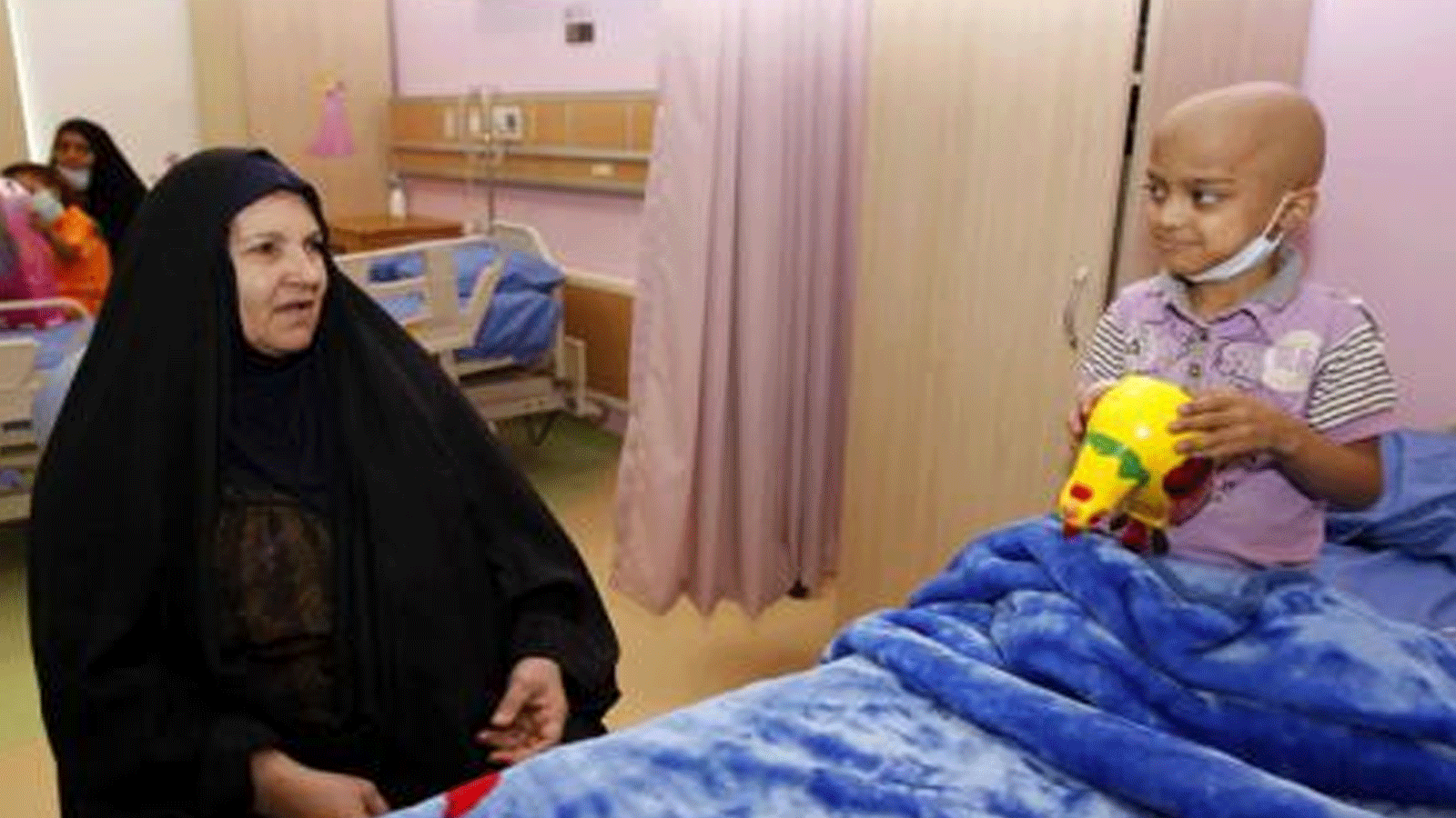 سيدة تلازم طفلاً مريضاً بالسرطان في بغداد