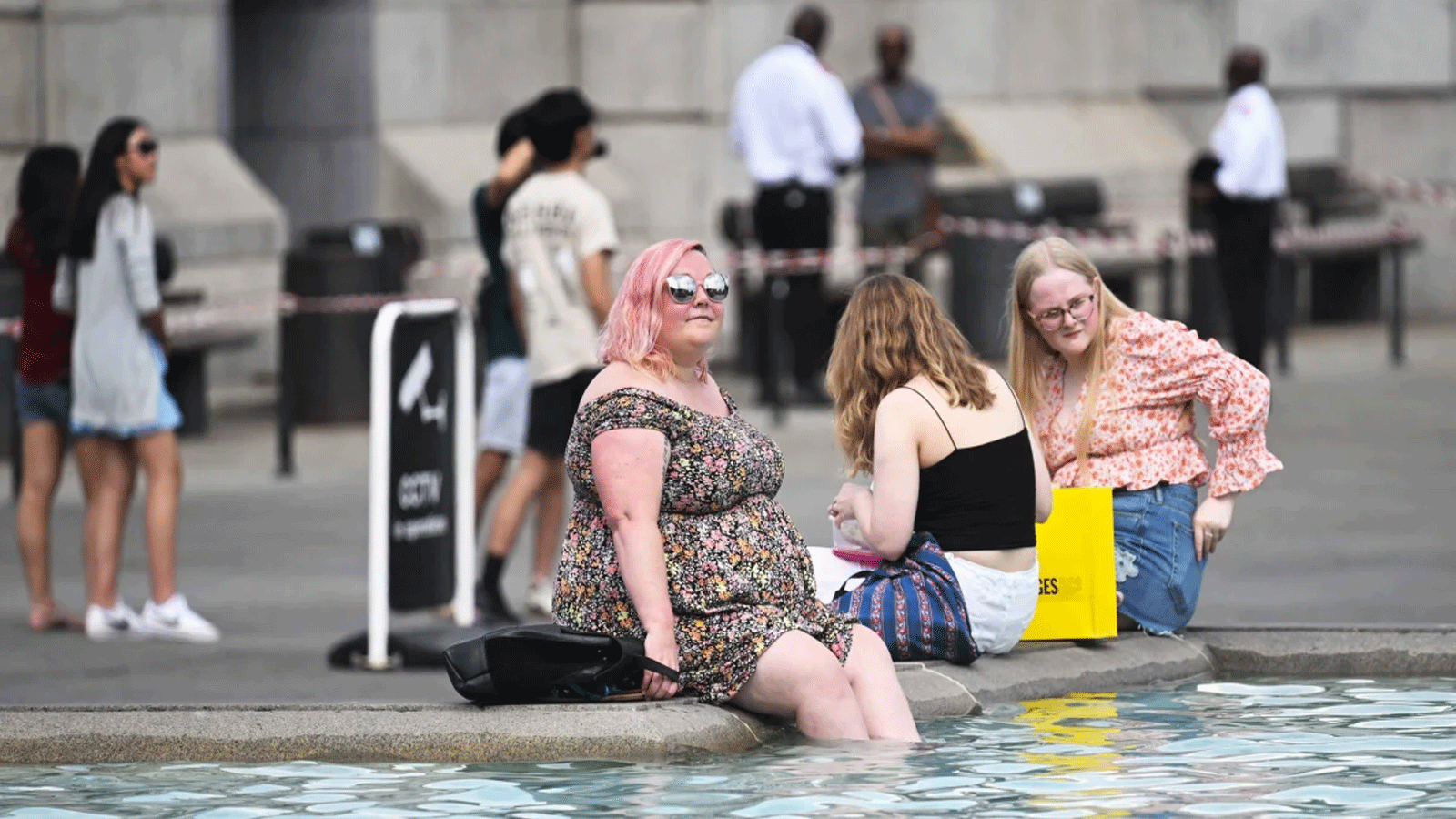 المشاة ينقعون أقدامهم في نافورة ترافالغار سكوير في لندن خلال موجة الحر