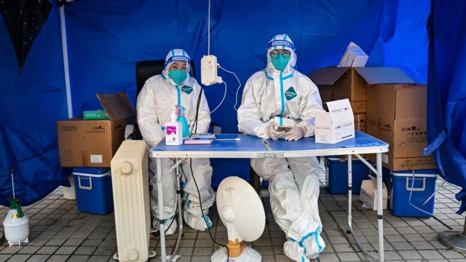 عاملان صحيان ينتظران لاستقبال أشخاص لإجراء اختبار كوفيد-19 لهم في منطقة جينغان في شنغهاي في 22 ديسمبر 2022 