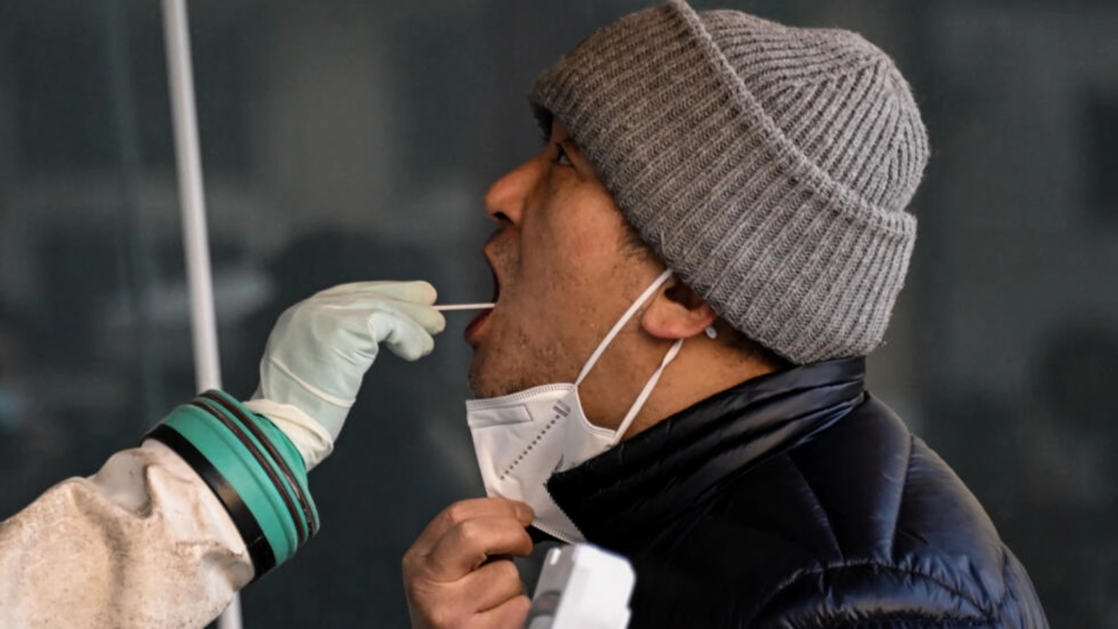 عامل صحي يأخذ عيّنة مسحة من رجل لفحصها بحثاً عن فيروس كورونا في مستشفى في بكين في 26 ديسمبر 2022