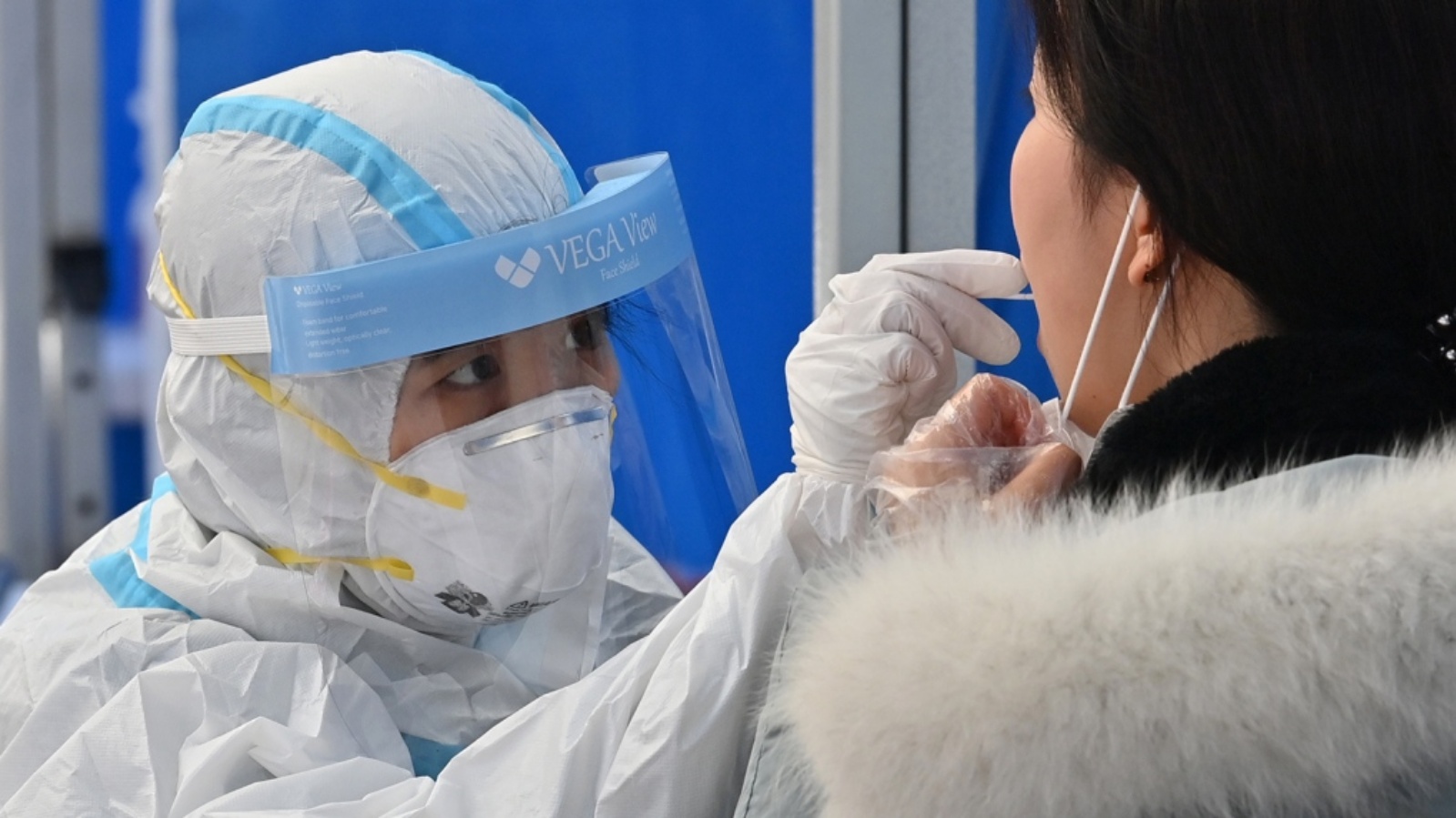 عامل صحة يرتدي ملابس واقية يأخذ عينات لاختبار كوفيد 19 من مريض في محطة اختبار في سيول في 27 نوفمبر 2020