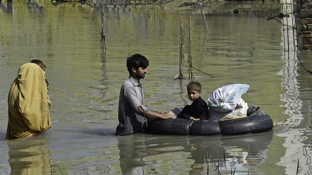 عائلة تخوض في منطقة ضربها فيضان بعد هطول أمطار موسمية غزيرة في منطقة شارسادا في خيبر بختونخوا في 29 أغسطس 2022