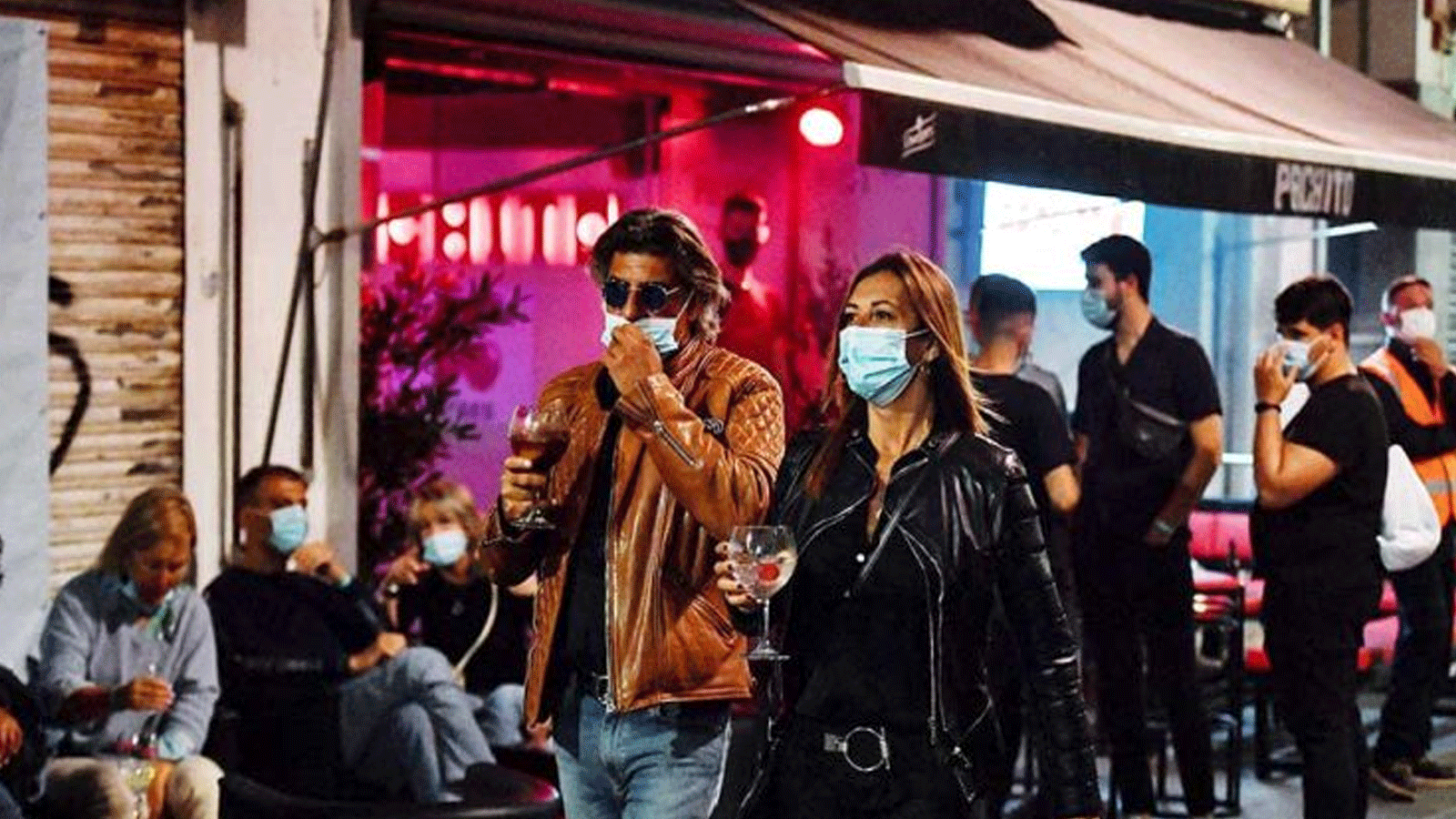 الناس يشربون في شرفة البار خلال حفلة ليلية في سيتجيس