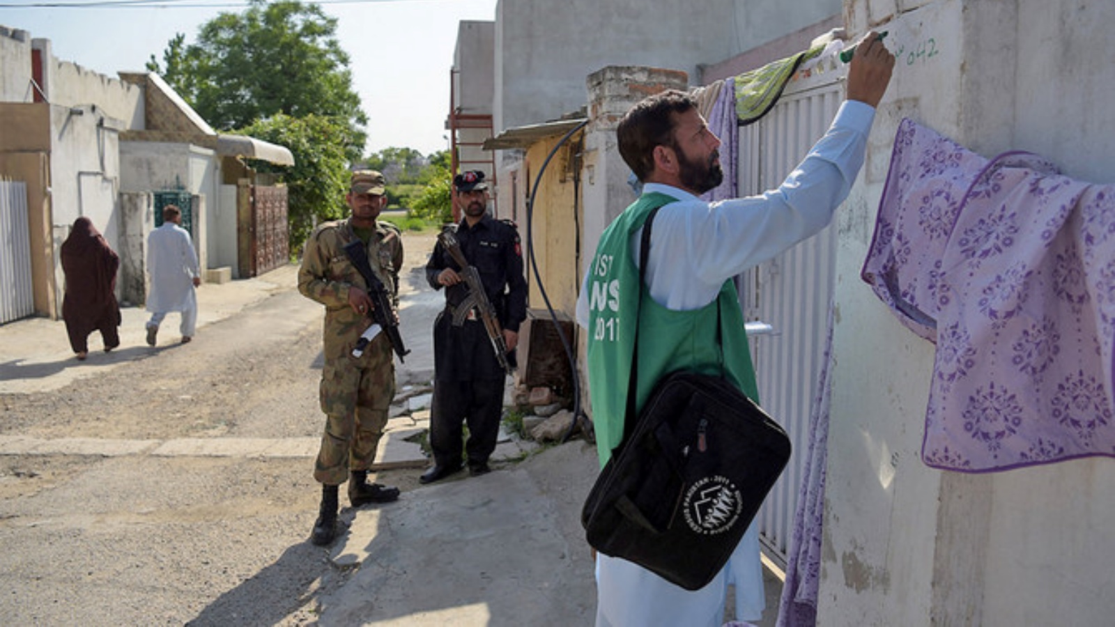 مسؤول من مكتب الإحصاء الباكستاني (يمين) يضع علامة على منزل بعد جمع معلومات من أحد السكان بينما يقف جنود باكستانيون في حراسة خلال المرحلة الثانية من التعداد الوطني في إسلام أباد، باكستان، في 25 أبريل 2017