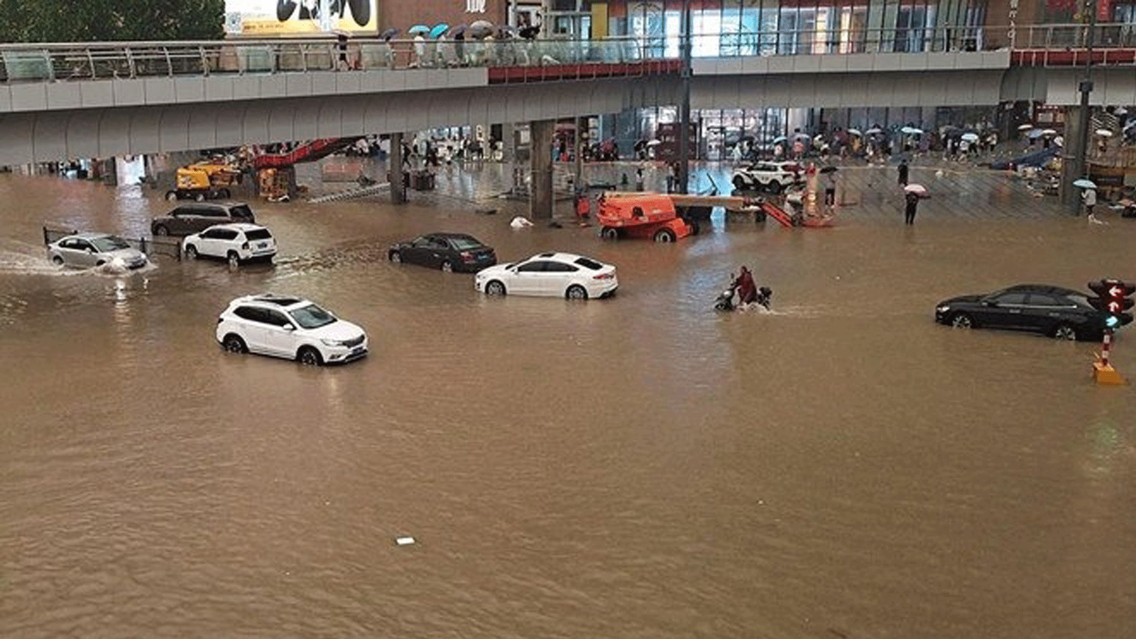 أشخاص عالقون في مياه الفيضانات على طول شارع بعد هطول أمطار غزيرة في مدينة تشنغتشو بمقاطعة خنان بوسط الصين. بتاريخ 20 تموز/ يوليو 2021