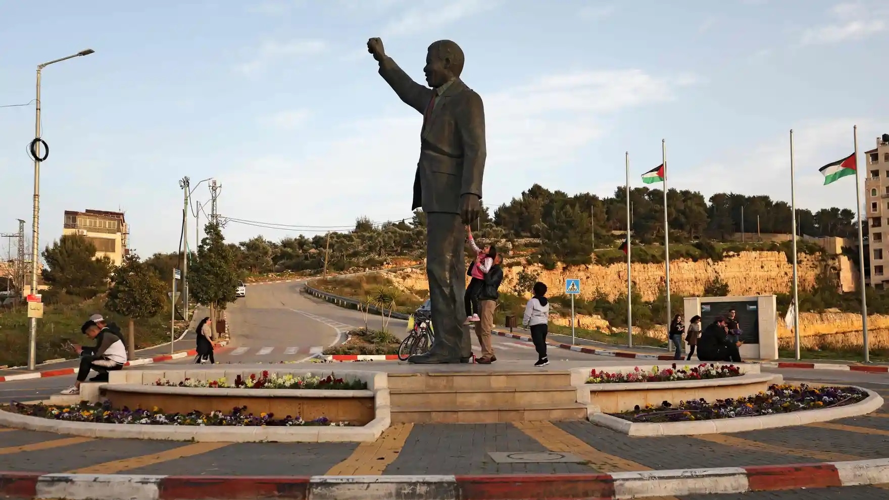 فلسطينيون قرب تمثال للرئيس الجنوب أفريقي الأسبق نلسون مانديلا قرب رام الله في الضفة الغربية