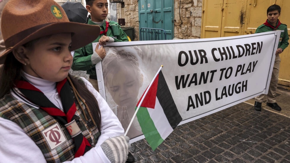 فتية فلسطينيون يحملون لافتة تدعو الى وقف الحرب في غزة