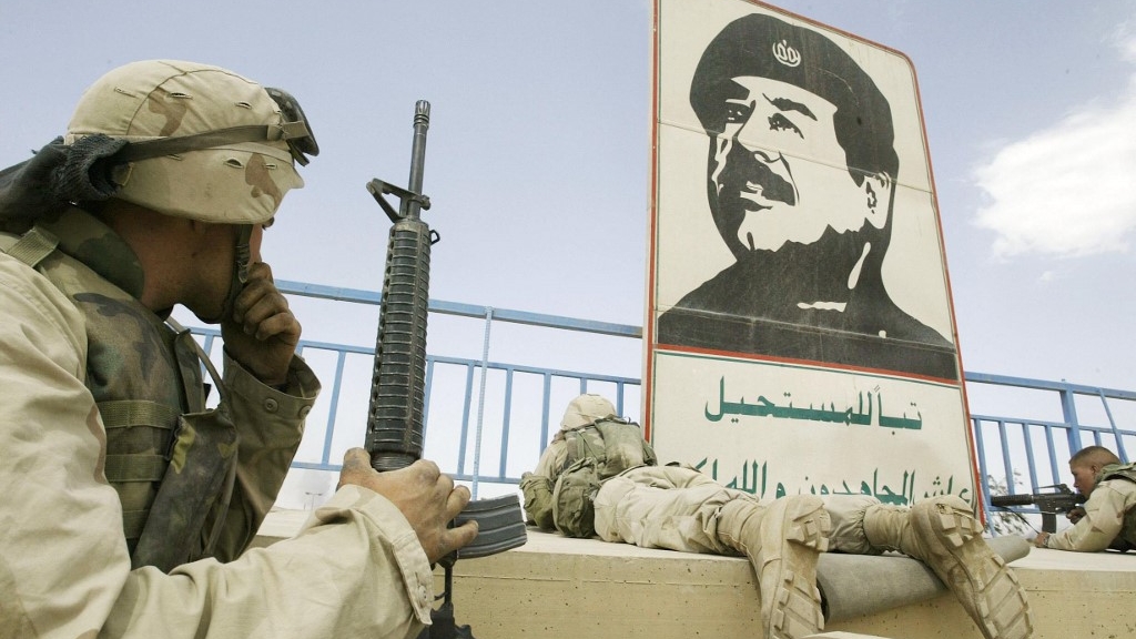 جنود أميركيون يتمركزون في ملعب في بغداد في 10 نيسان (أبريل) 2003 وتبدو صورة للرئيس العراقي الأسبق صدام حسين