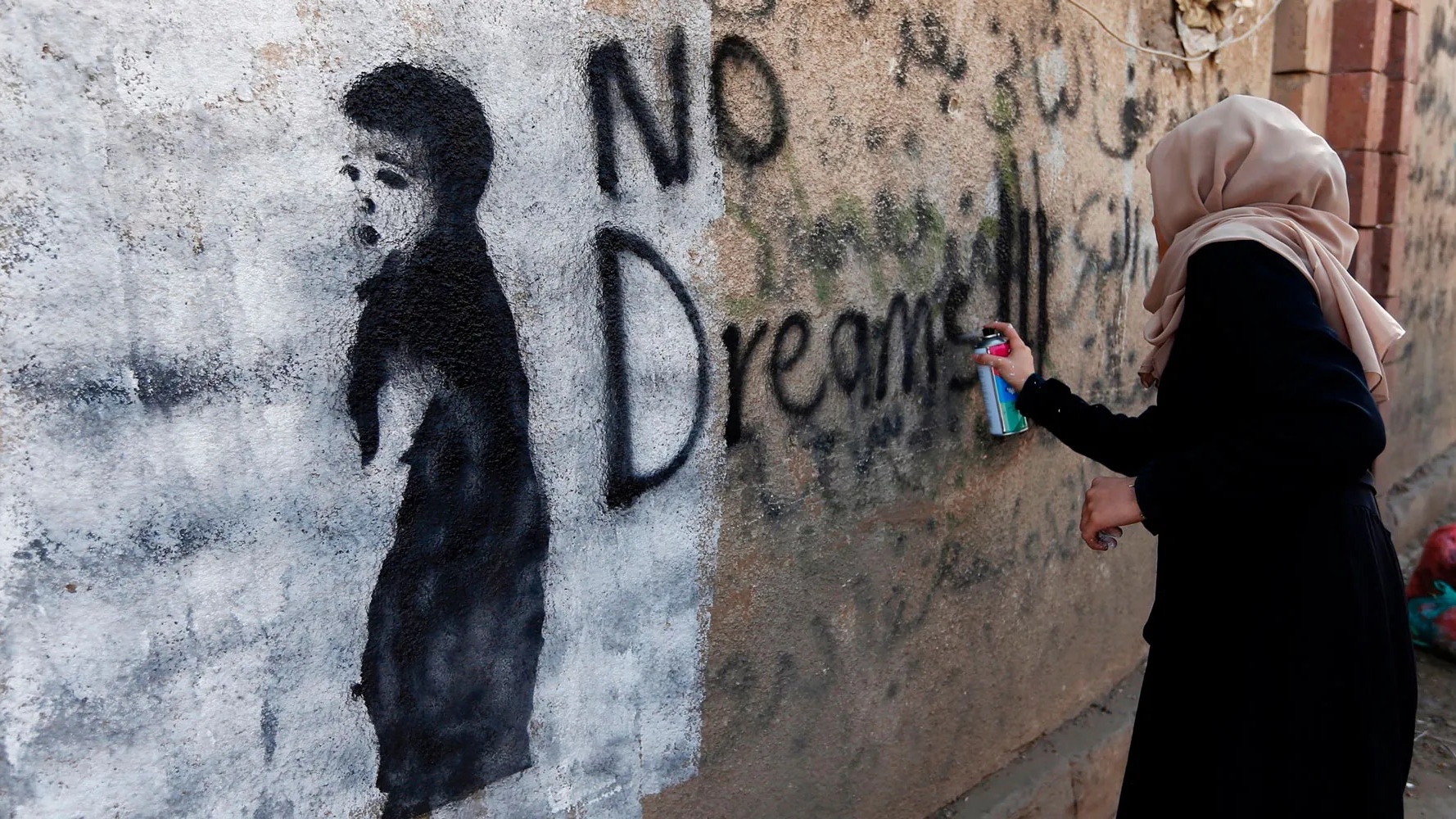 امرأة تكتب فوق جدارية في صنعاء طلباً للسلام في العام 2017
