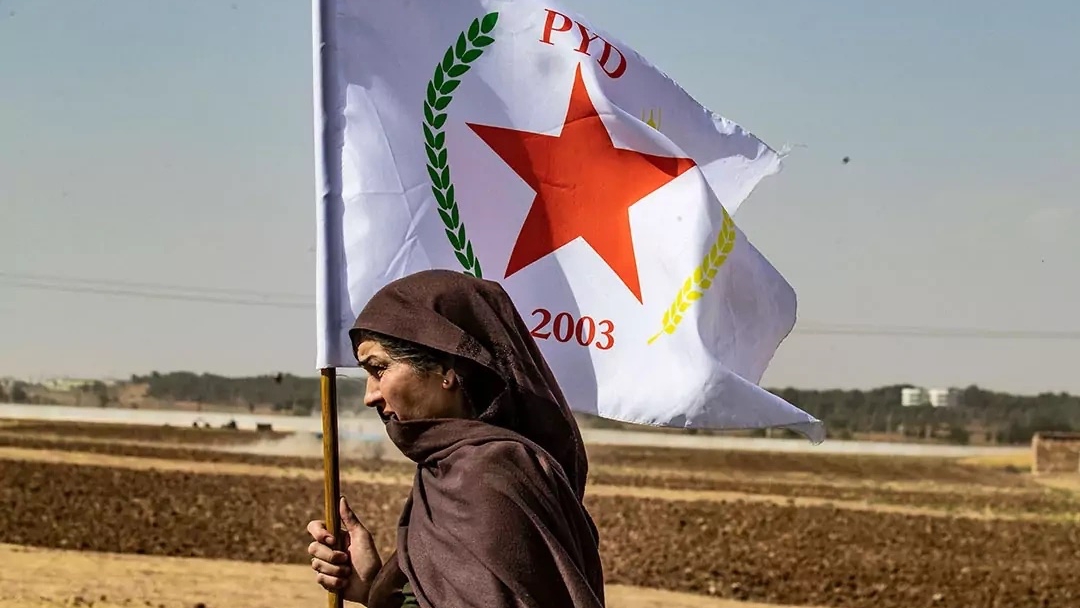 امرأة ترفع علم حزب الاتحاد الديمقراطي في شمال سوريا