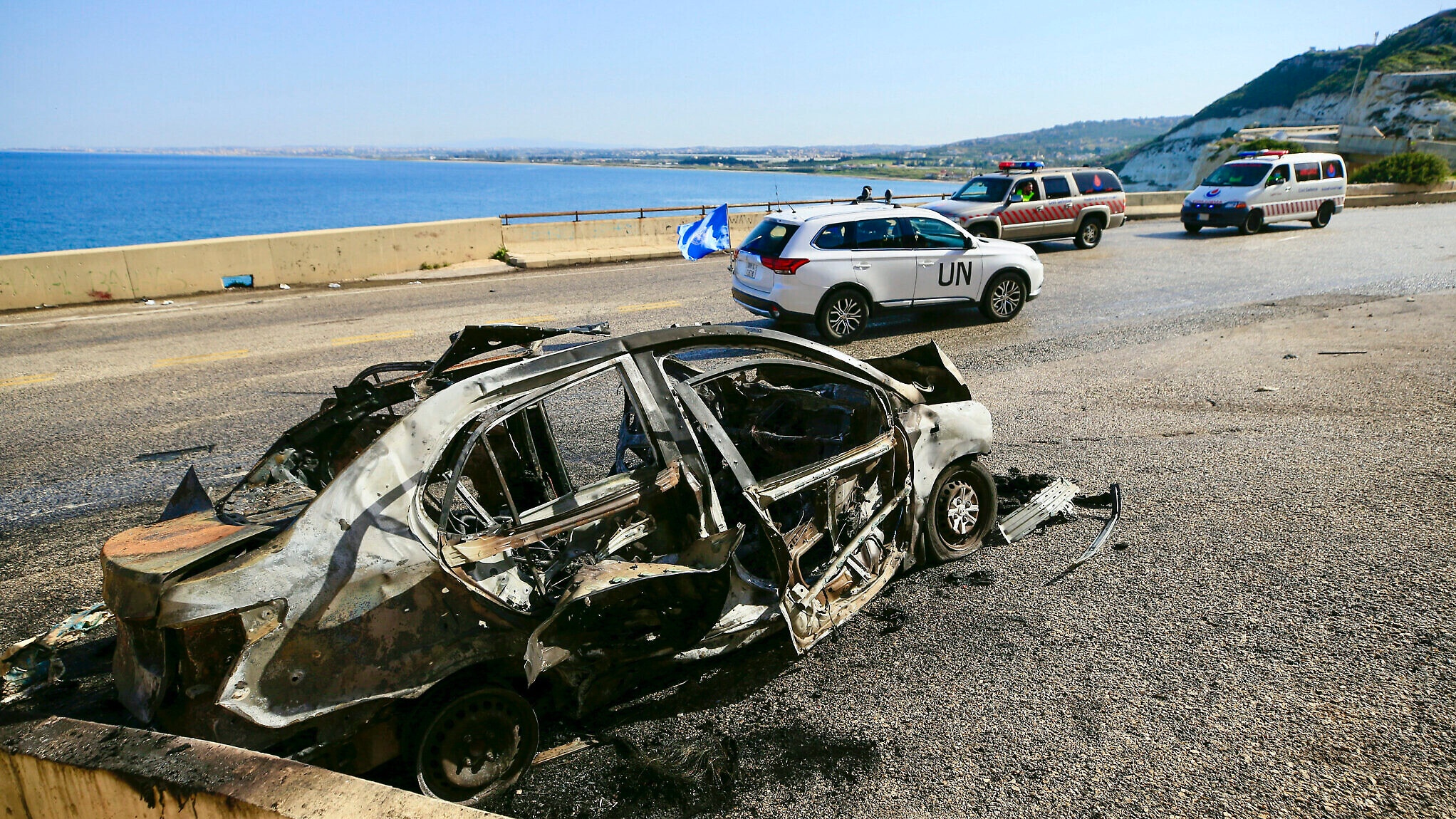 سيارة تابعة لقوات اليونيفيل العاملة في جنوب لبنان تمر بالقرب من سيارة قصفتها إسرائيل في الناقورة، في 2 آذار (مارس) 2024