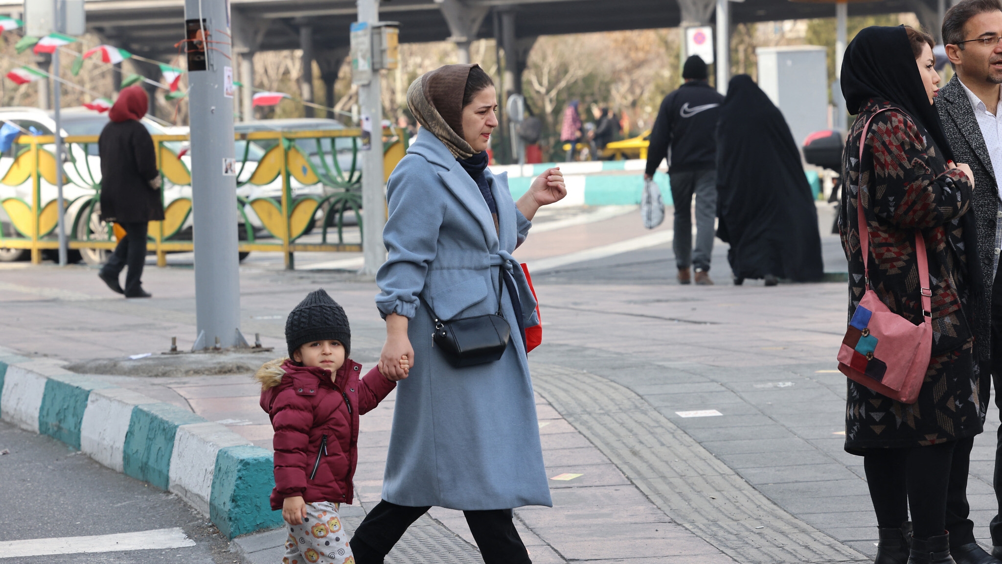 امرأة تسير بصحبة طفل في طهران في الثالث من آذار (مارس) 2024، بعد يومين فقط من انتخابات شهدت إقبالاً شعبياً ضعيفاً