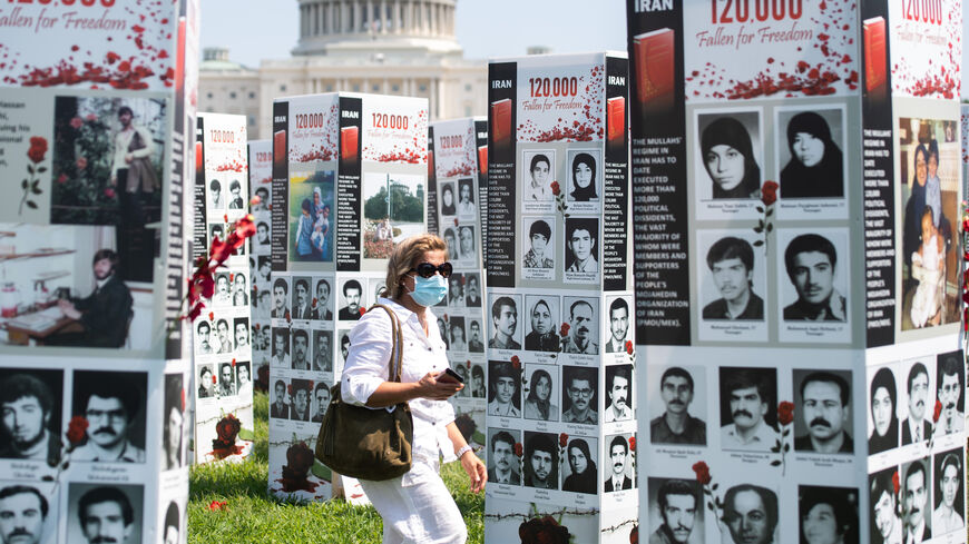 امرأة تسير في واشنطن بالقرب من صور مئات الذي أعدمهم النظام الإيراني بتهمة انتمائهم إلى المعارضة في مذبحة العام 1988