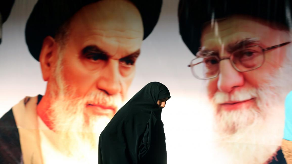 إيرانية أمام ملصق للخميني وخامنئي في طهران