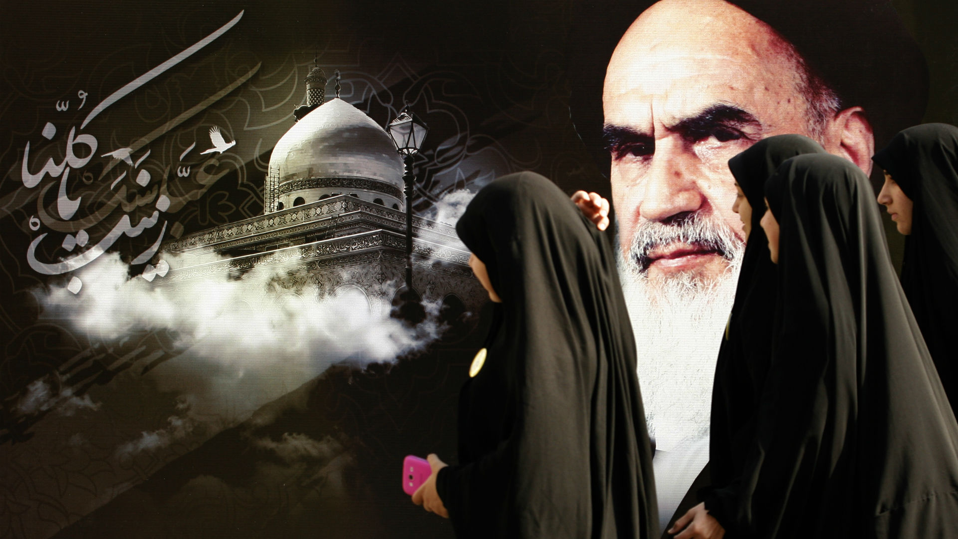 نساء يسرن أمام جدارية عليها رسم الخميني في طهران